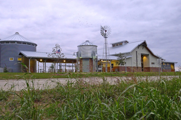 Back view shows a working windmill, and a grain-bin like structure that houses a restroom